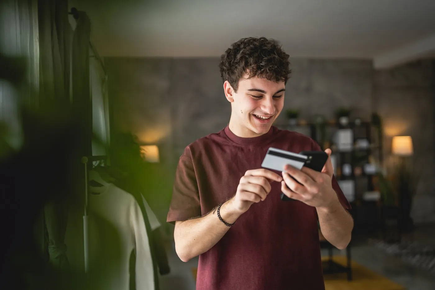 A teenage young man using a credit card for shopping online.