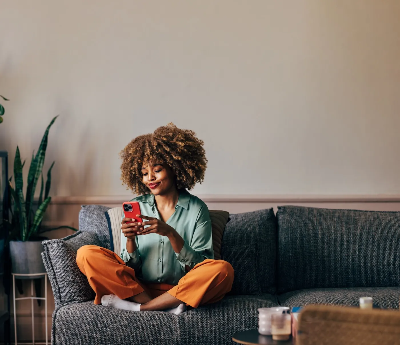 A smiling elegant woman using her smartphone while sitting on the cozy sofa in the living room.