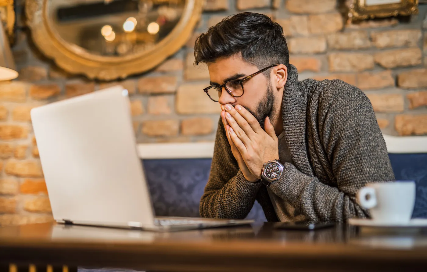 Young man looking at computer in disbelief.