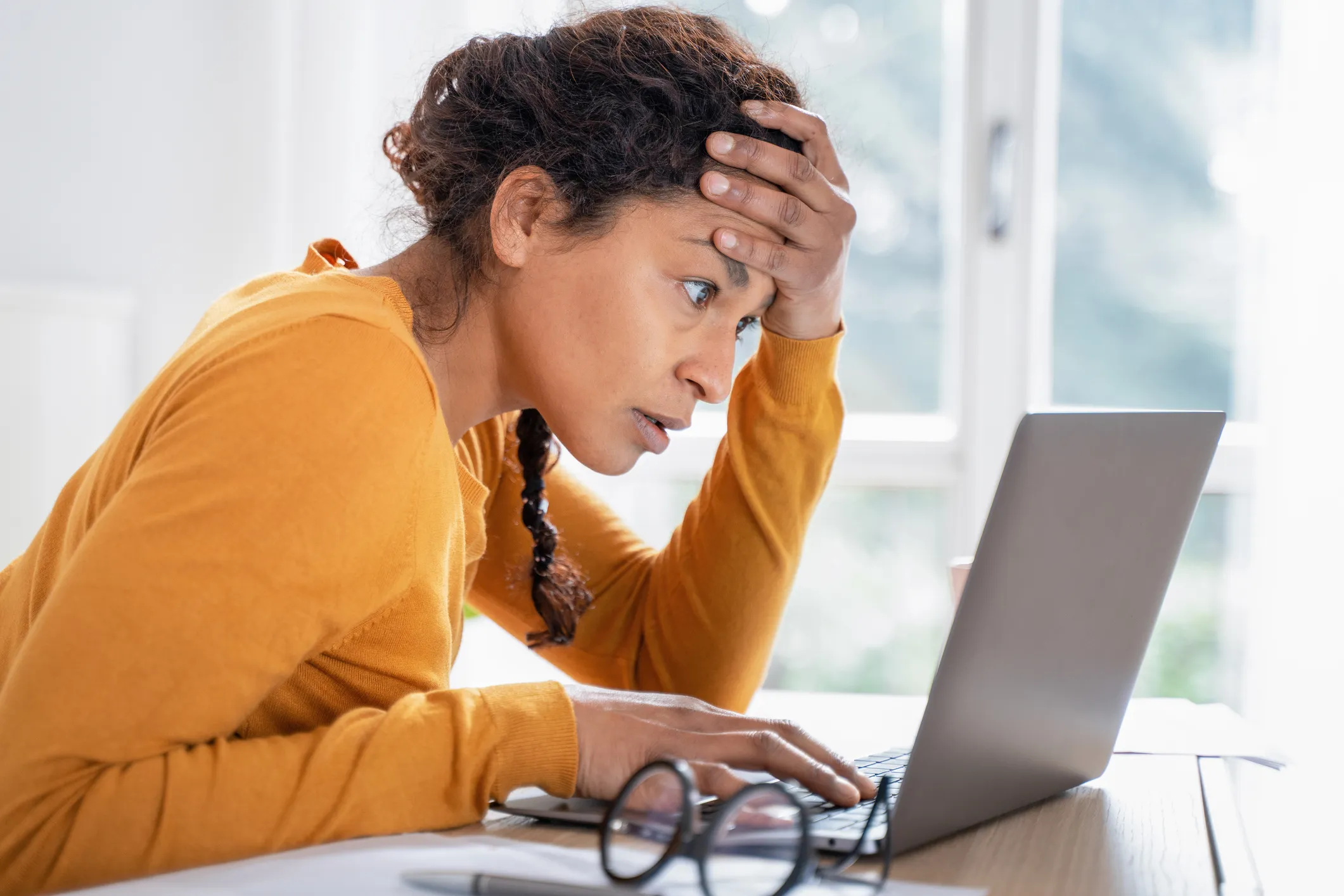 A woman worried, reading her laptop.