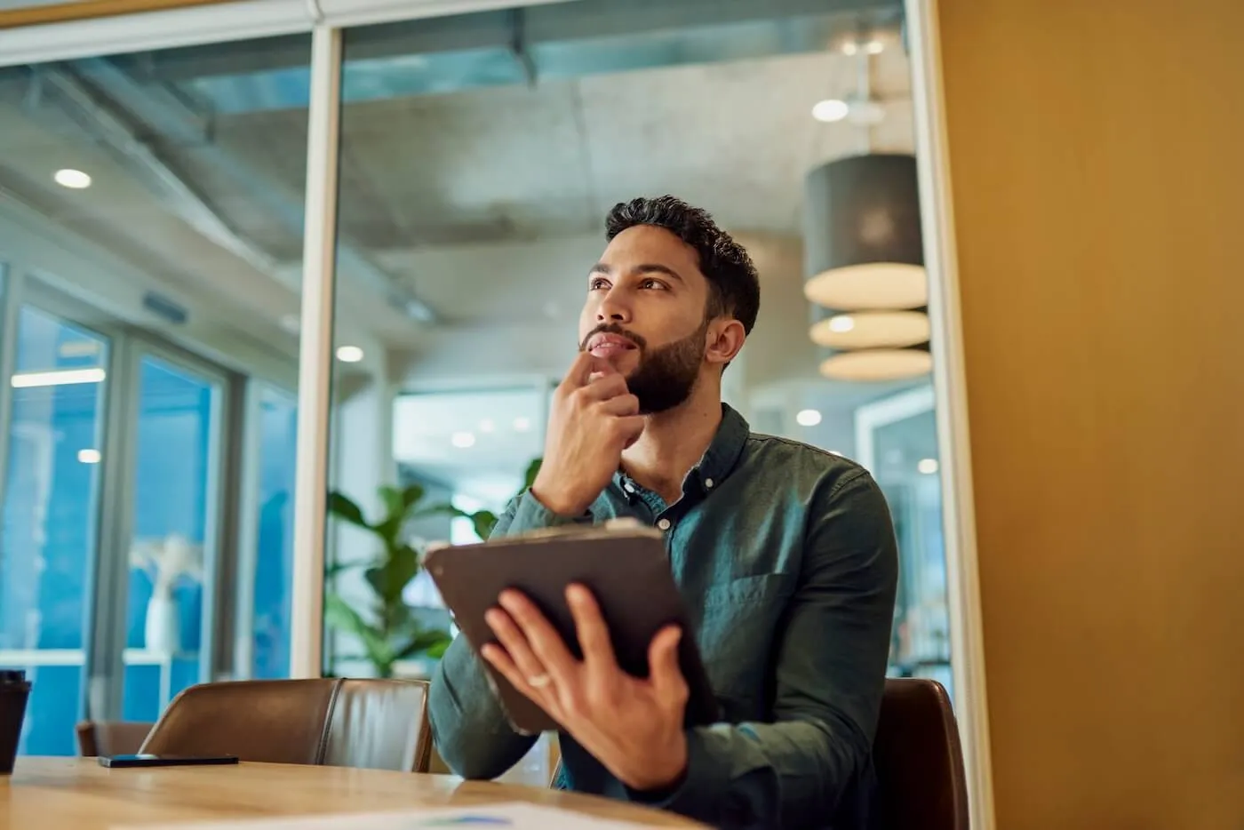 Young businessman looks thoughtfully into the distance while holding a tablet