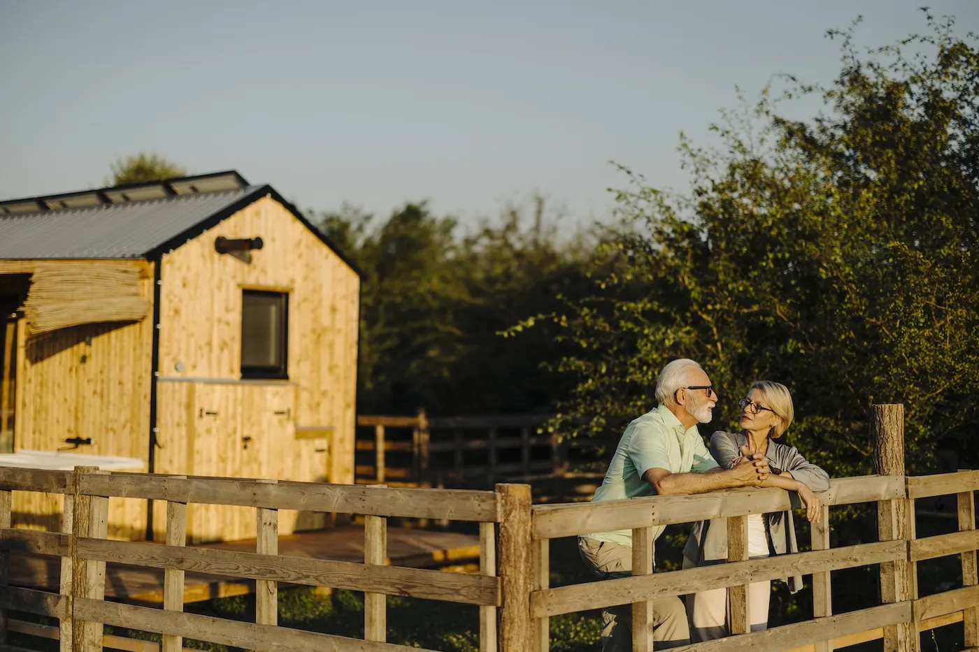 A senior couple standing in front of their house.