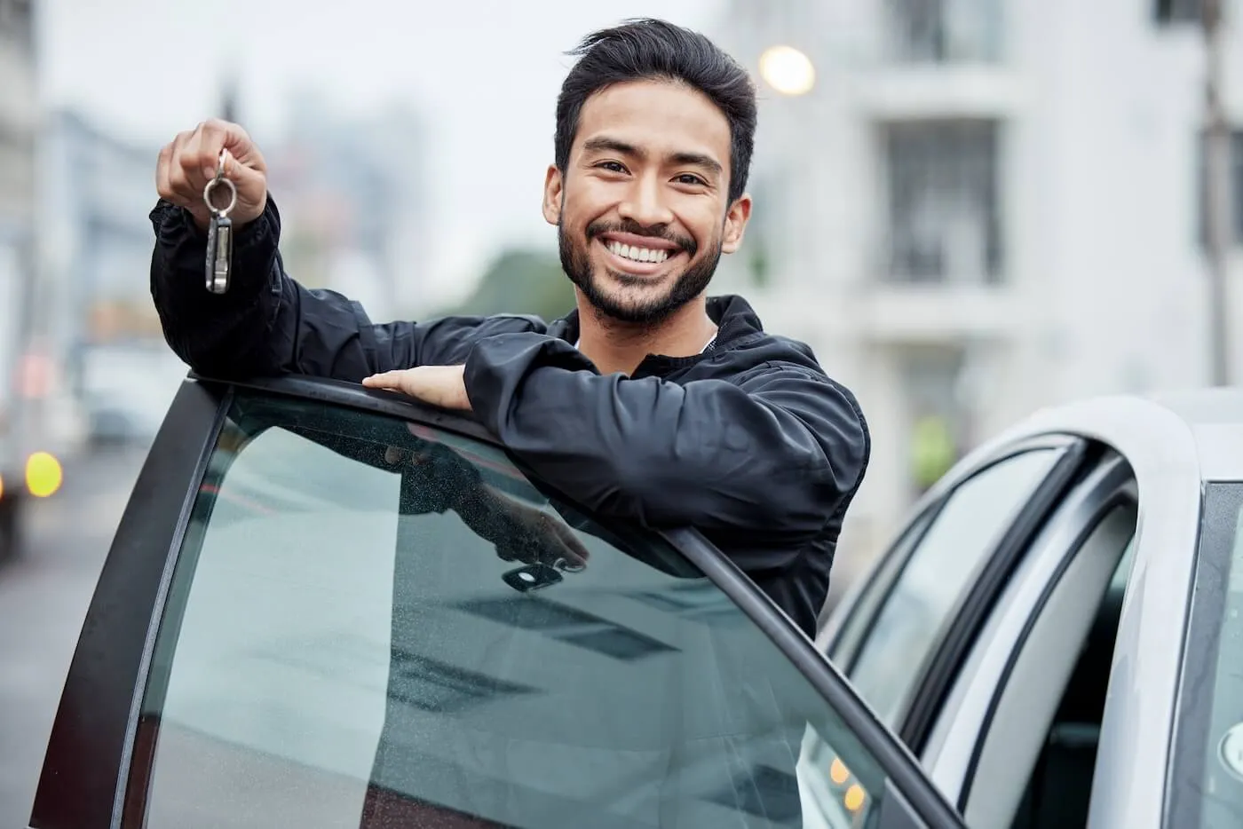 Smiling man leaning towards the car door while holding the keys