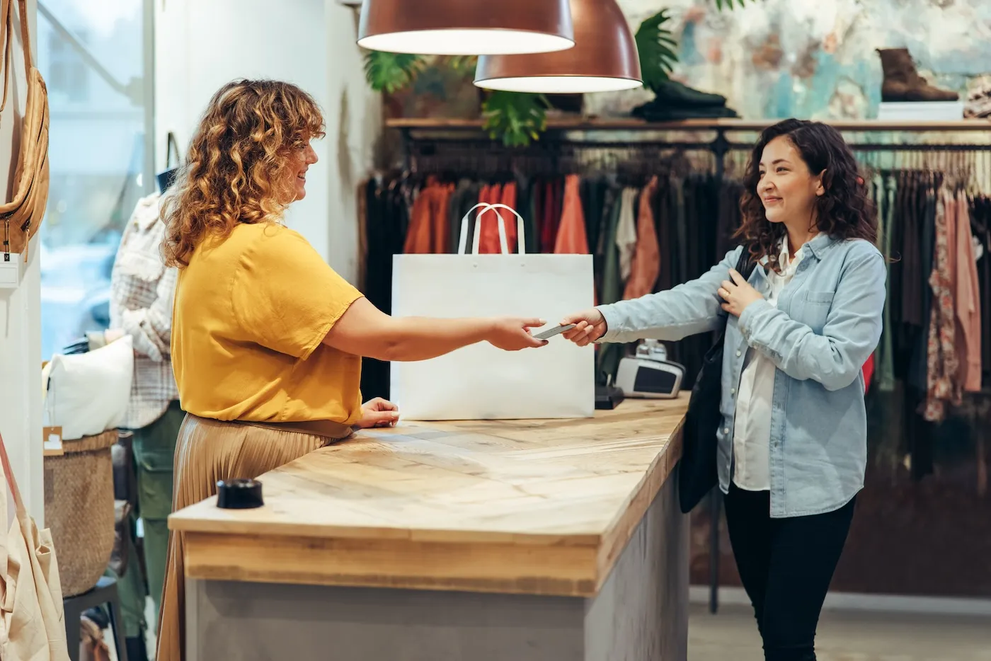 Woman giving her credit card for a contactless payment in the fashion store.