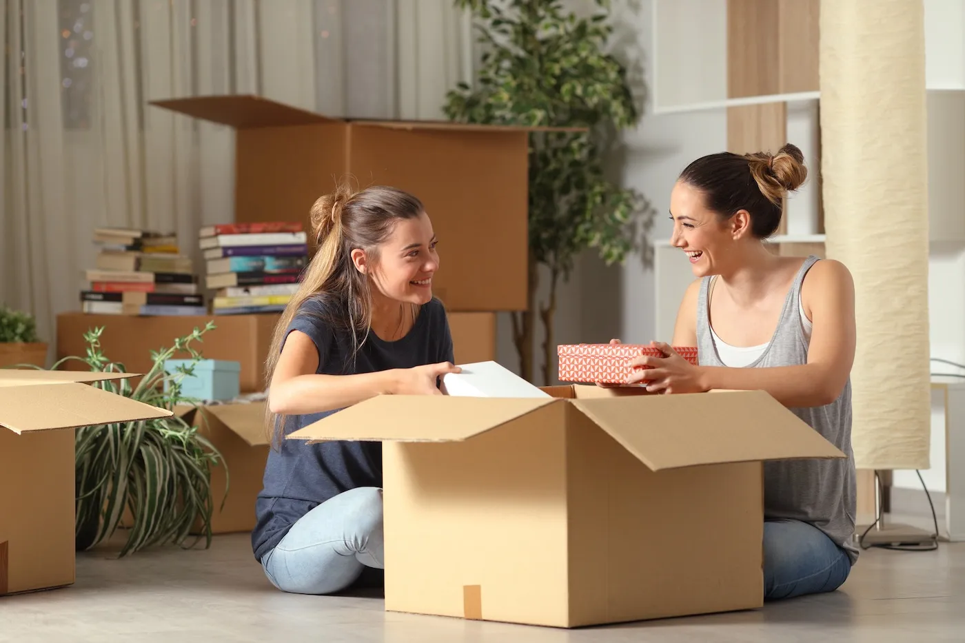 Two women talking and unboxing belongings while moving into their new rental home.