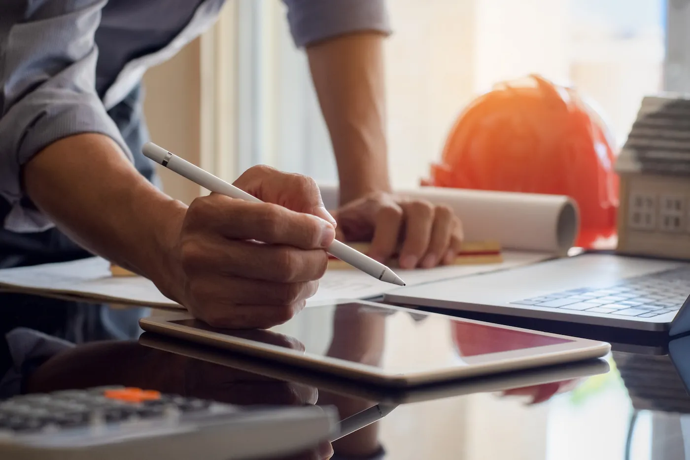 Applying for credit on tablet with stylus and papers surrounding on a desk.