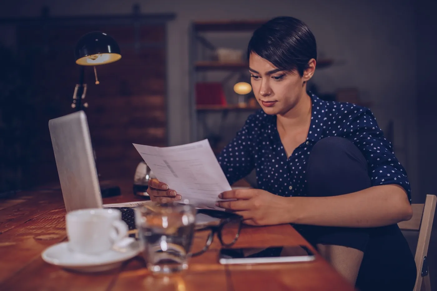 One woman, sitting in office, working late and reading some tax document.