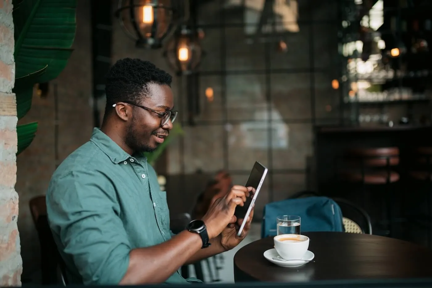 Smiling man using his tablet while having coffee in the cafe