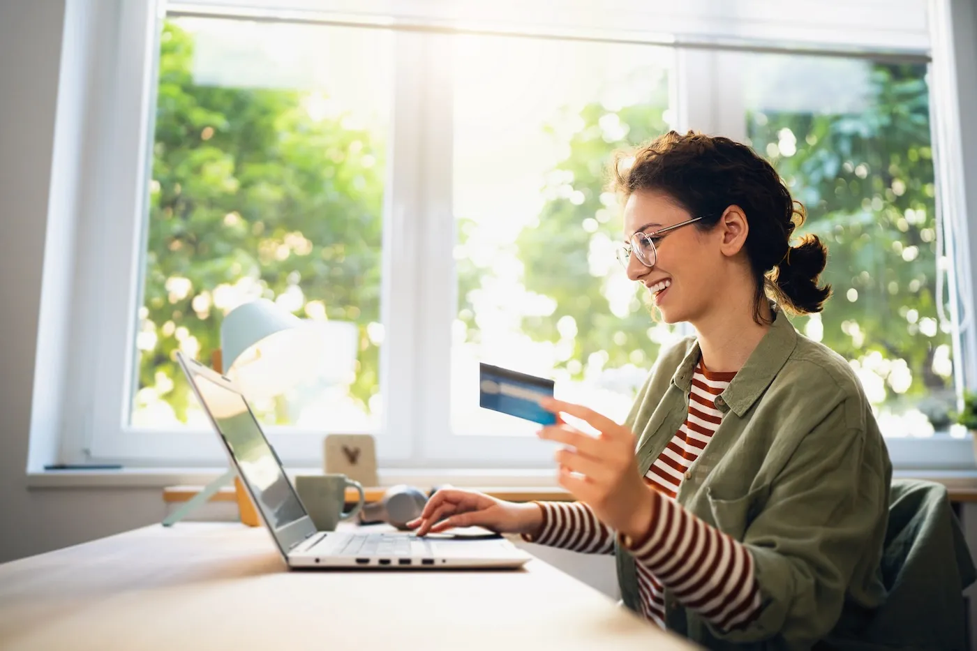 Young woman shopping online from her home with a credit card.