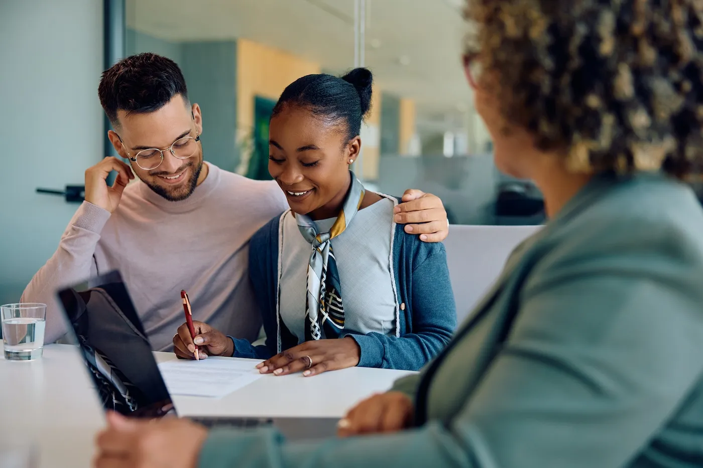 A man and a woman signing an agreement with their real estate agent during a meeting in the office.