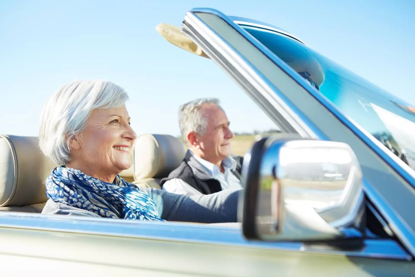 Happy senior couple driving a convertible