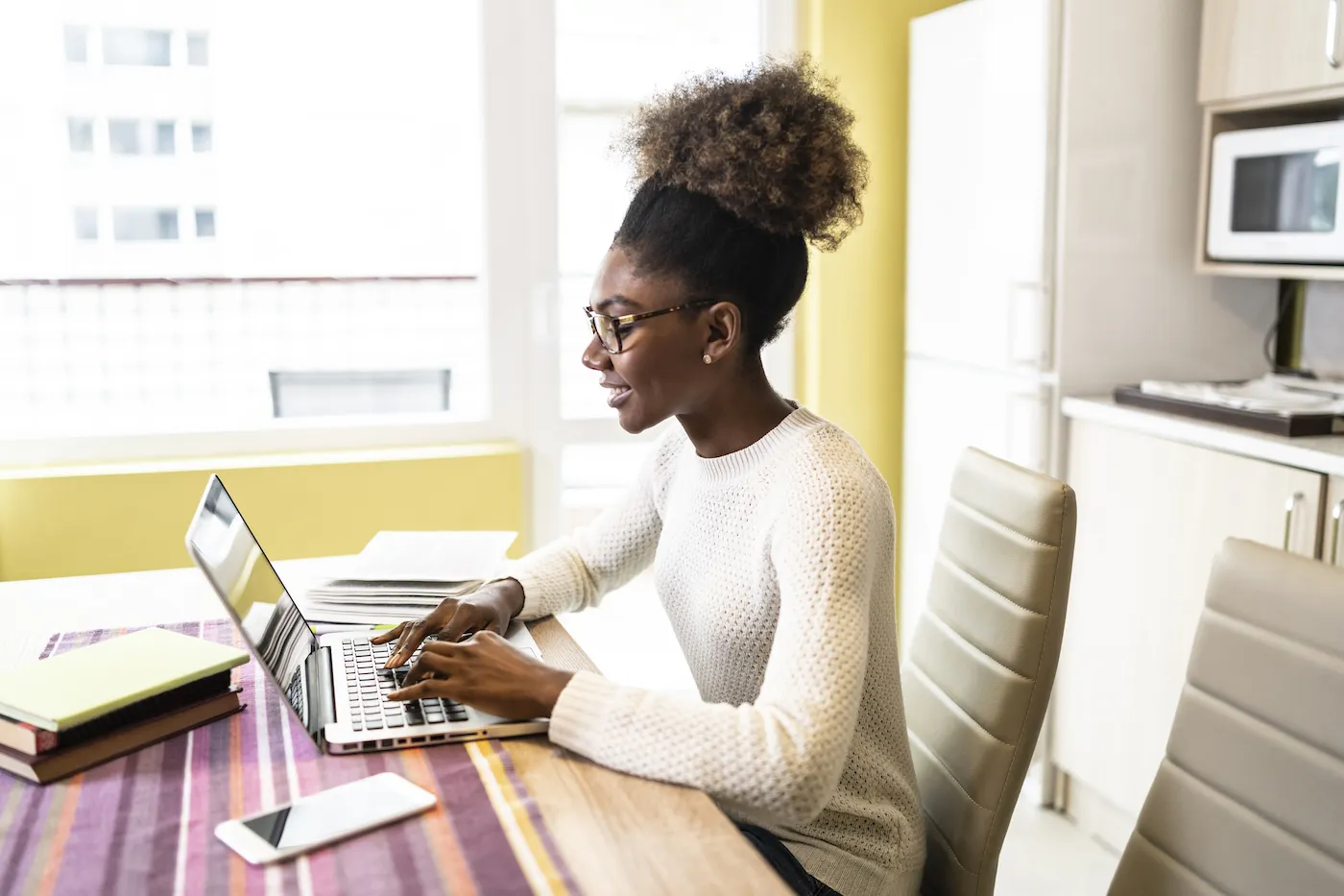 Side view of woman working at home, using laptop.