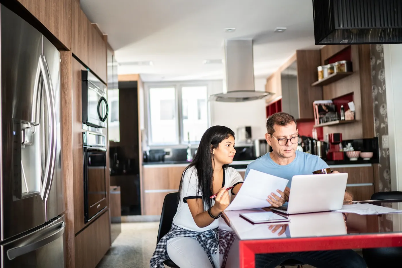 Father and daughter doing home finances together at home.