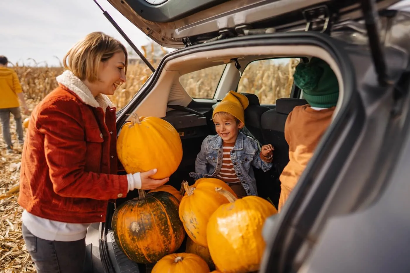 A mother with two kids loading the pumpkins into the car trunk