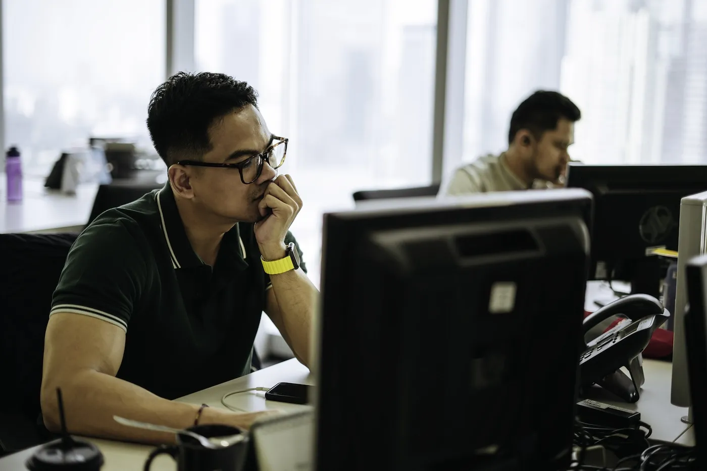 Shot of a young man frowning while using a laptop in a modern office.