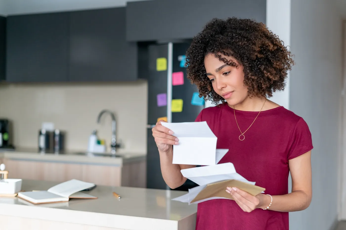 Portrait of a woman at home reading a bill in the mail.