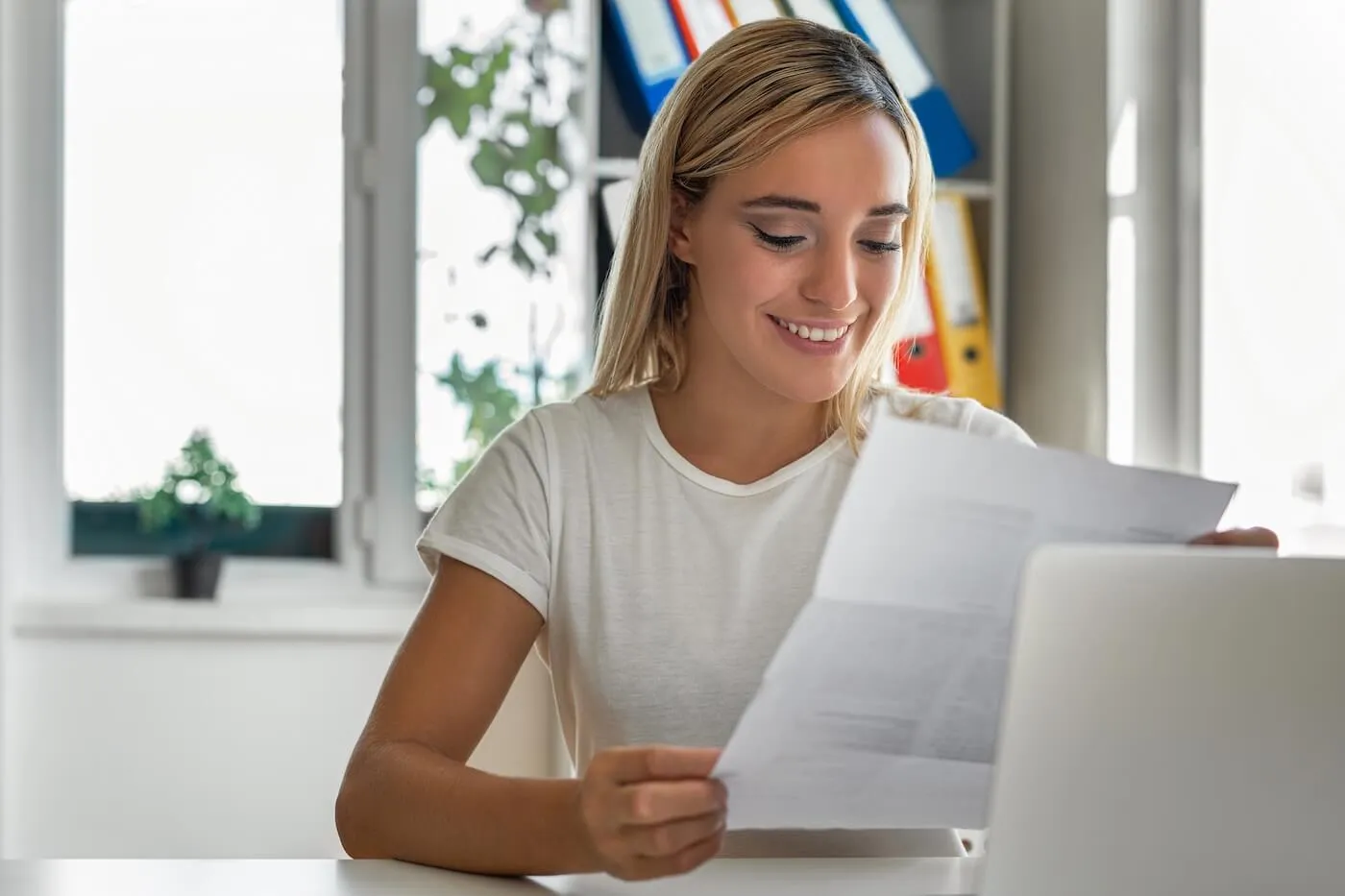 Smiling woman reviewing her resume printout in home office