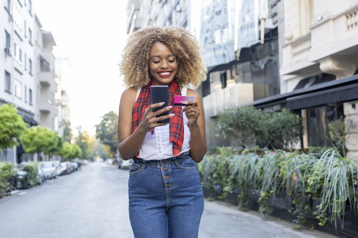 Cheerful young woman holding credit card and a phone