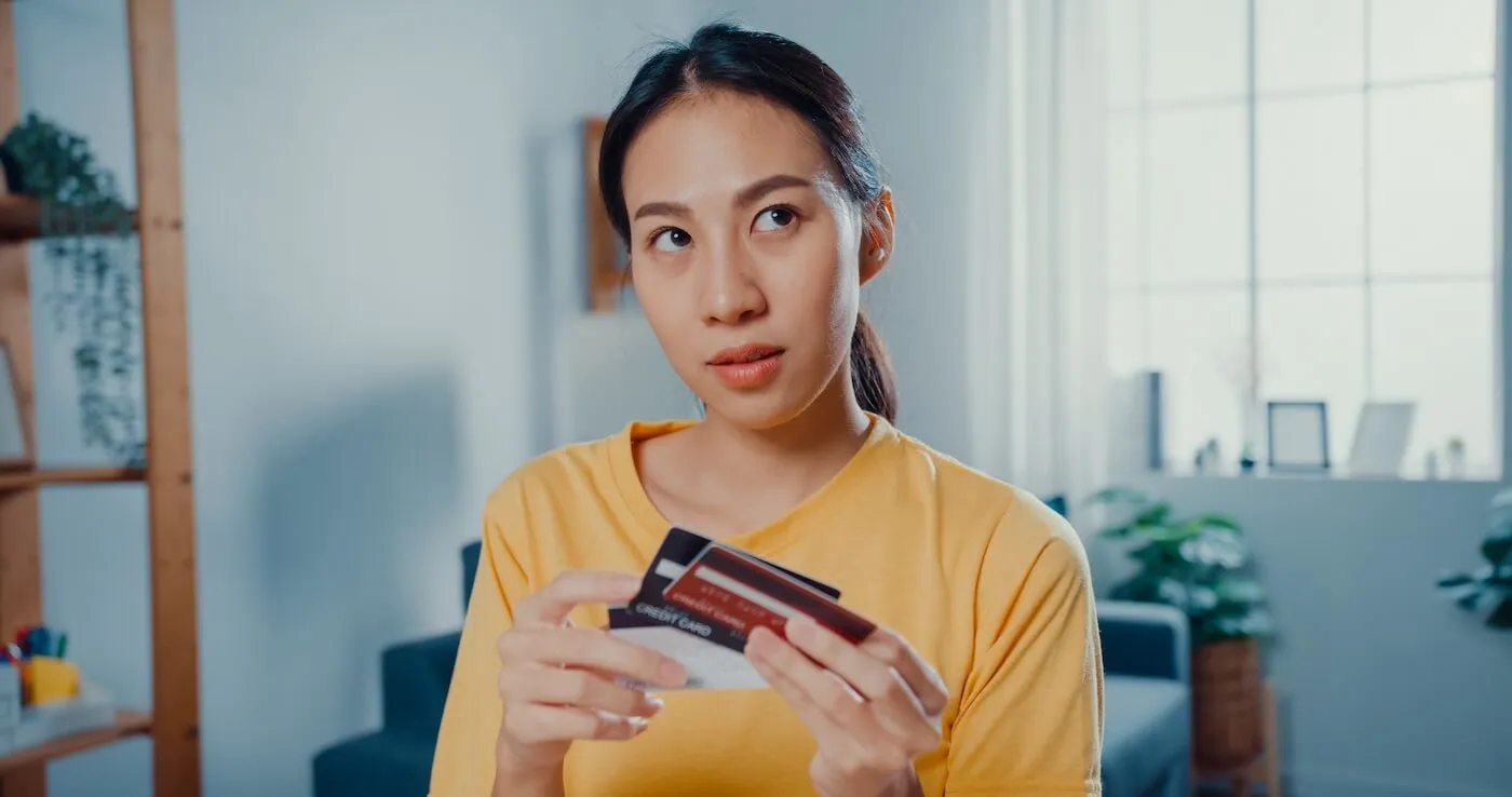 A concerned young woman holding credit cards