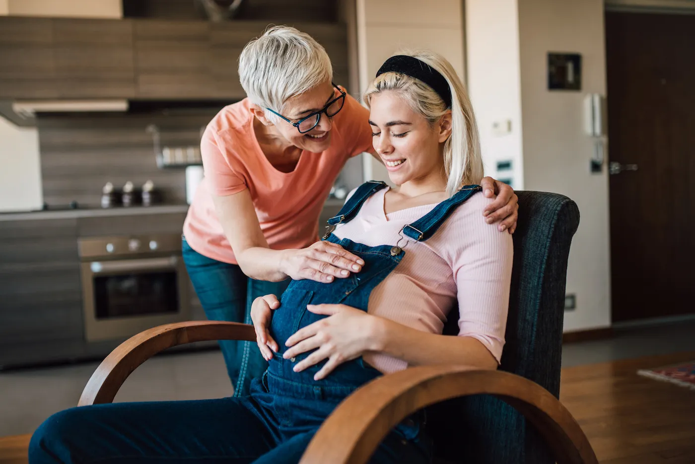 Young pregnant woman allowing her mother to touch her belly