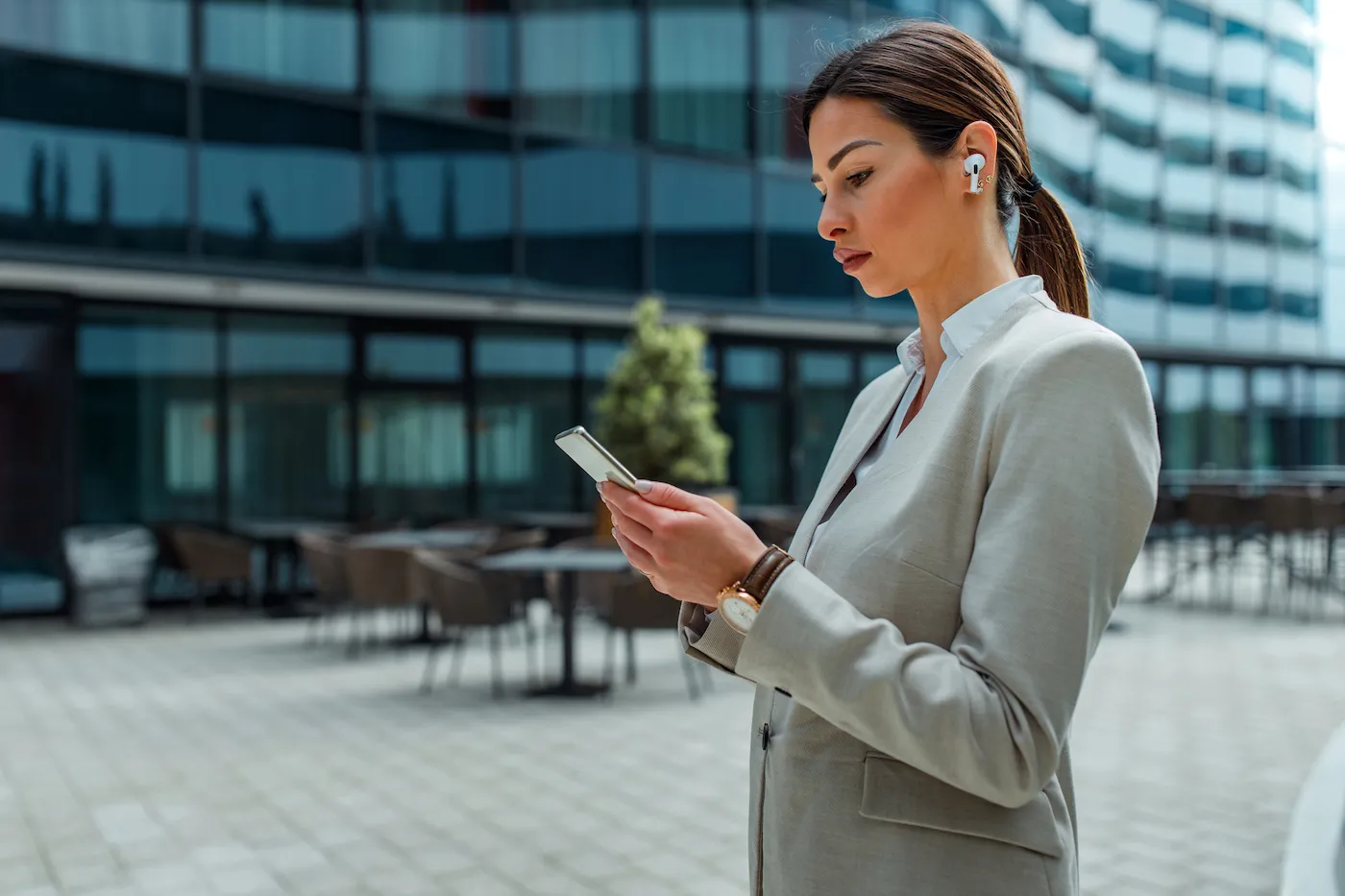 Young businesswoman in front of her bank using cellphone