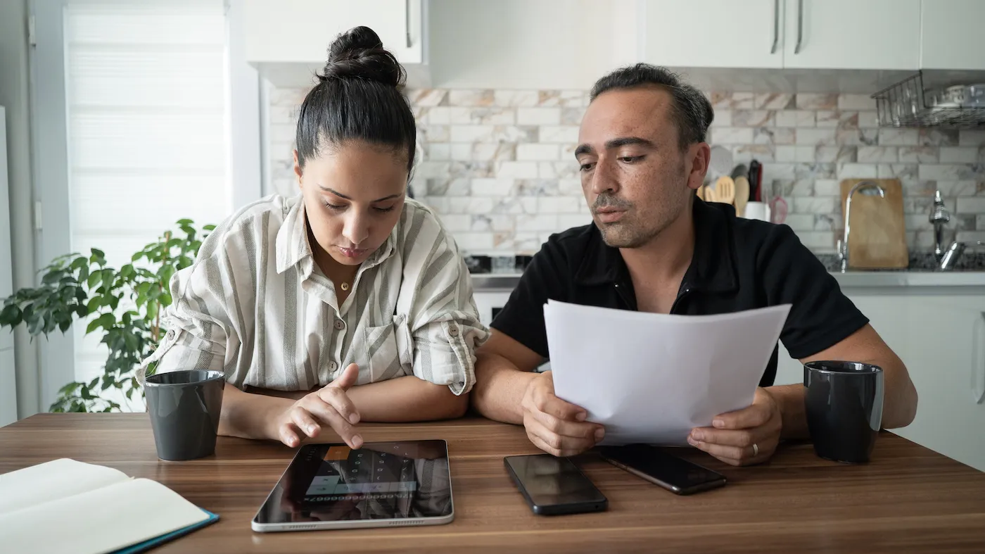 A couple working on their respective finances at home.