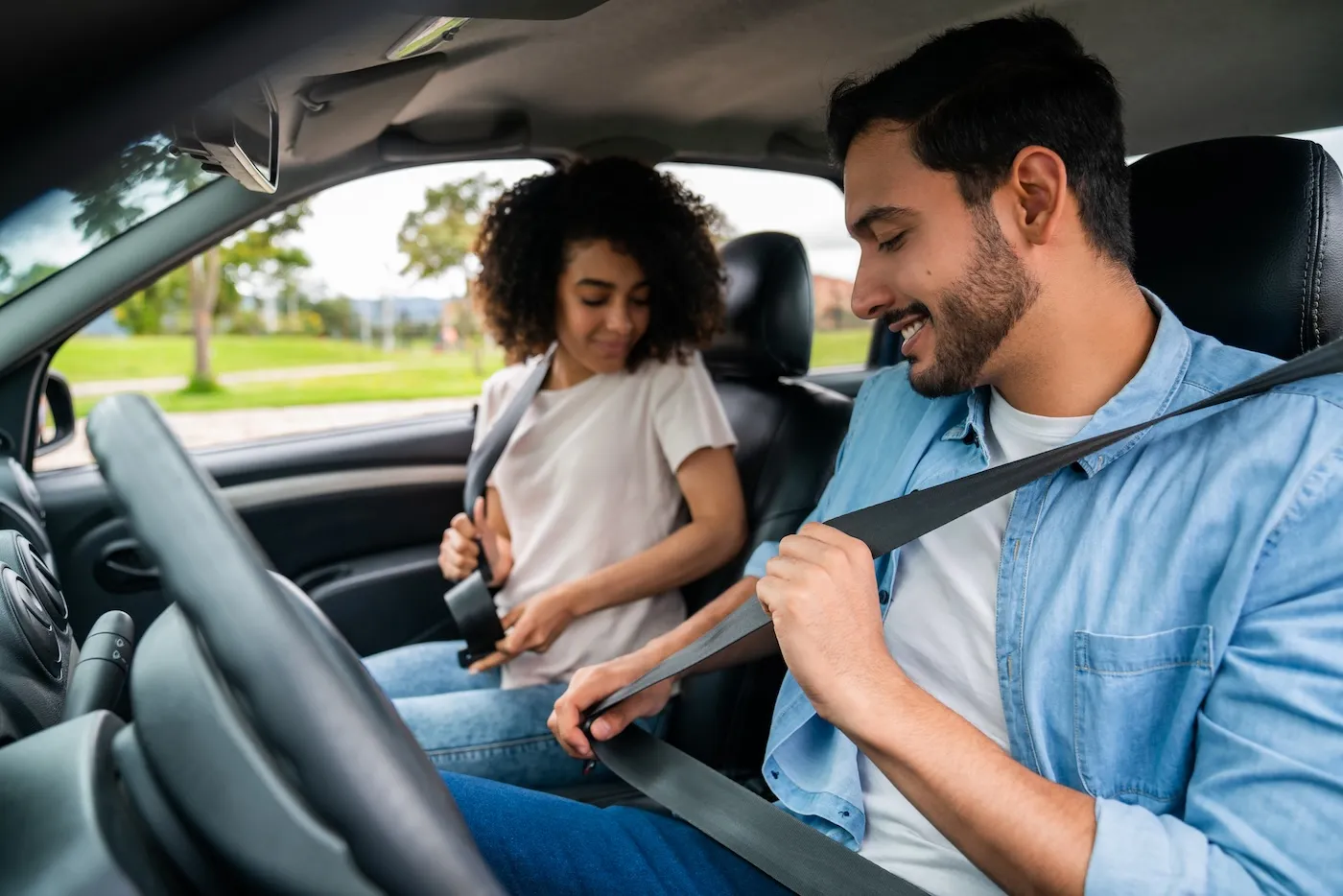 Young couple in a car fastening their seat belts.