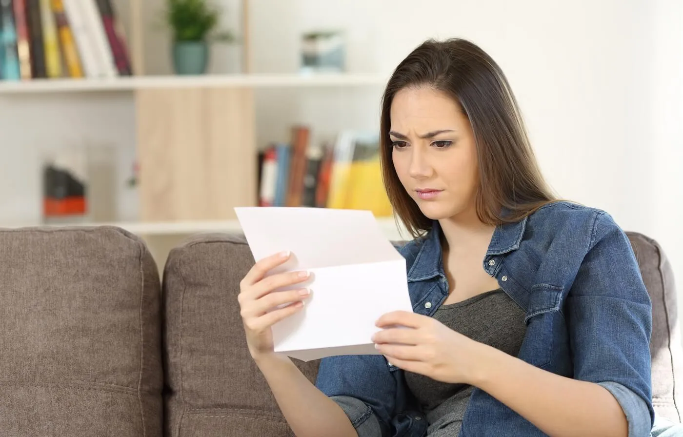 A concerned woman is reading a letter