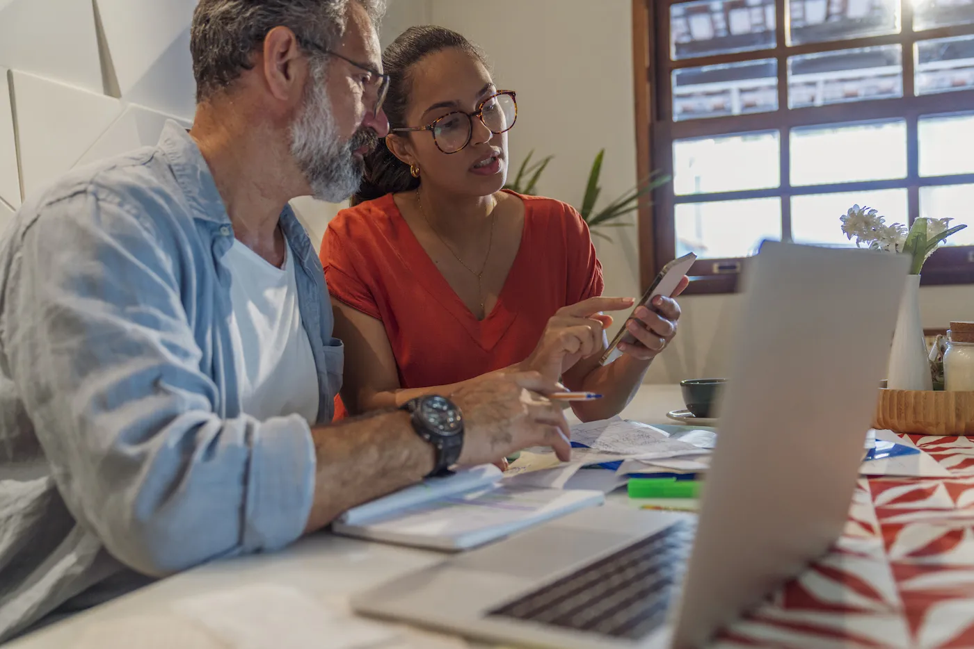 Photo of senior man and his daughter checking a savings account using a phone.