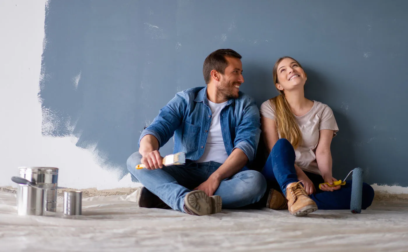 Man and woman taking a break from painting wall.