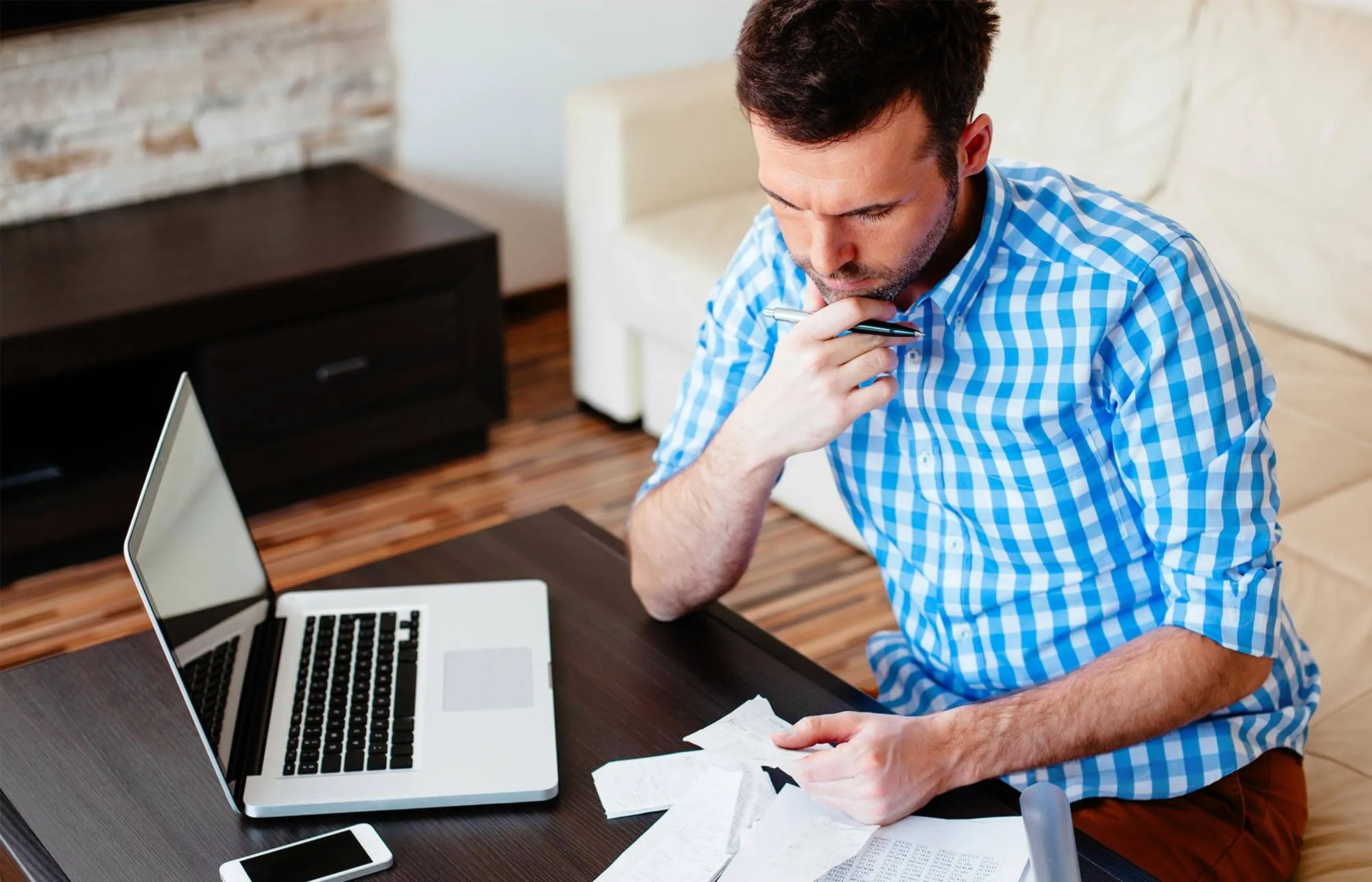 A man reviewing documents with a laptop.