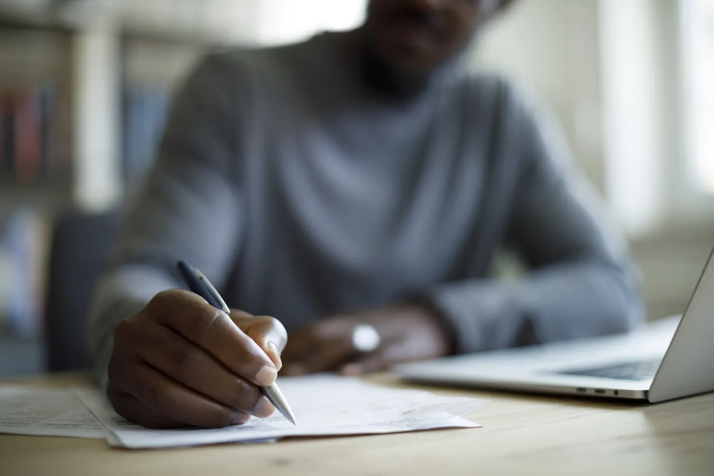 Man doing his taxes writing on a piece of paper with a pen