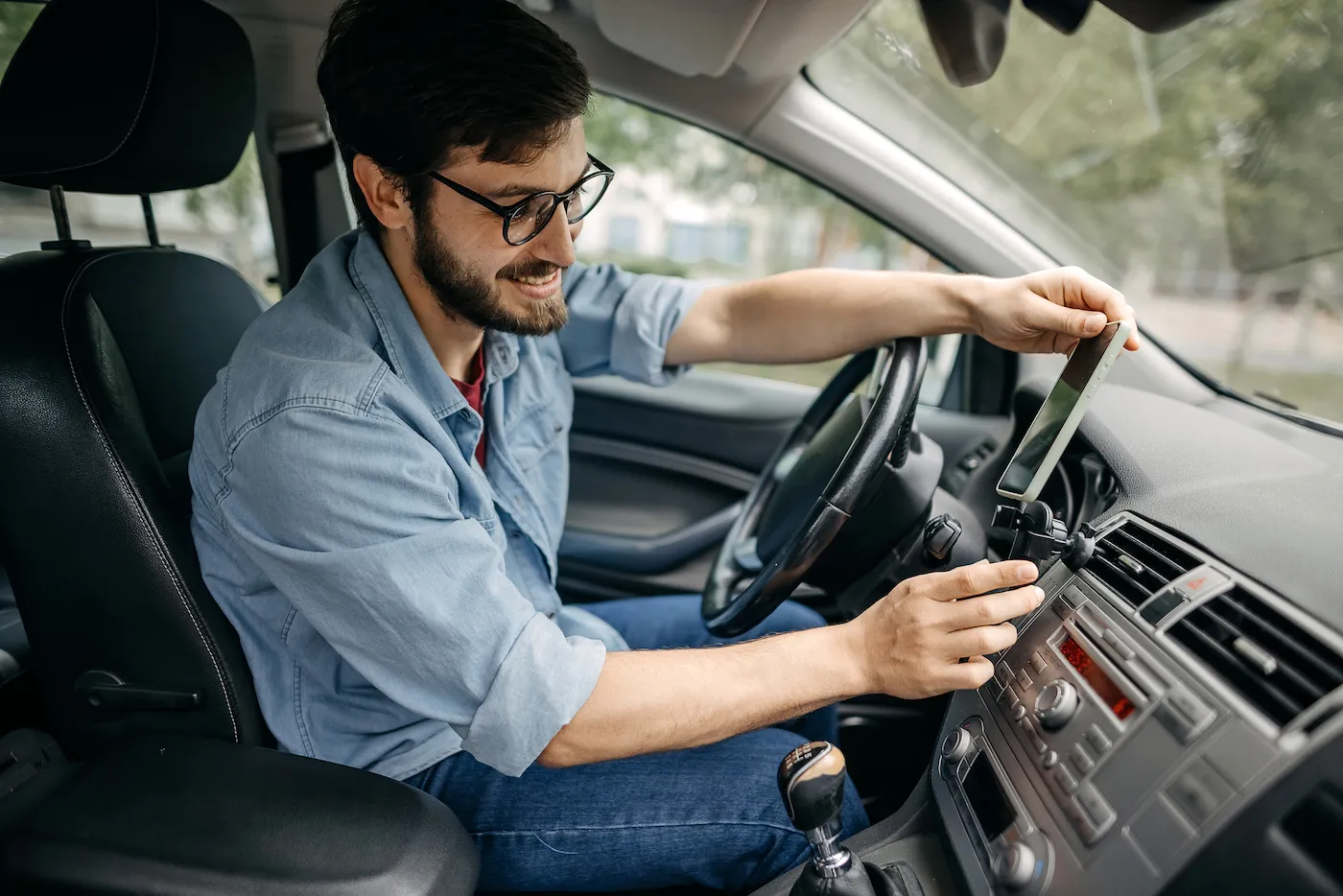 Young man driving a car and changing radio station