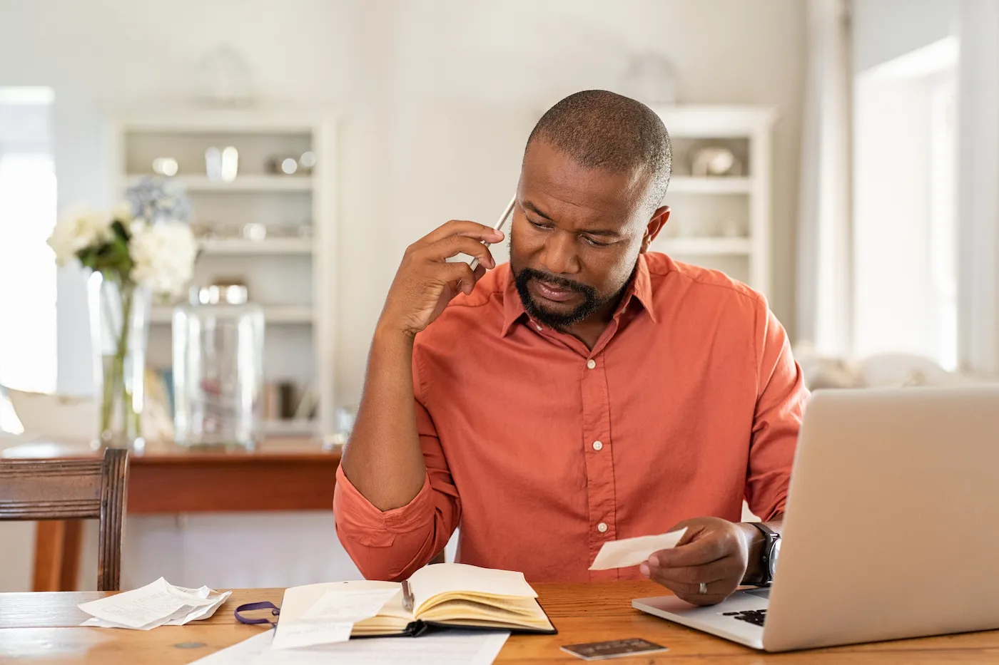 Man sitting at a desk with a laptop and papers, making a debt management plan