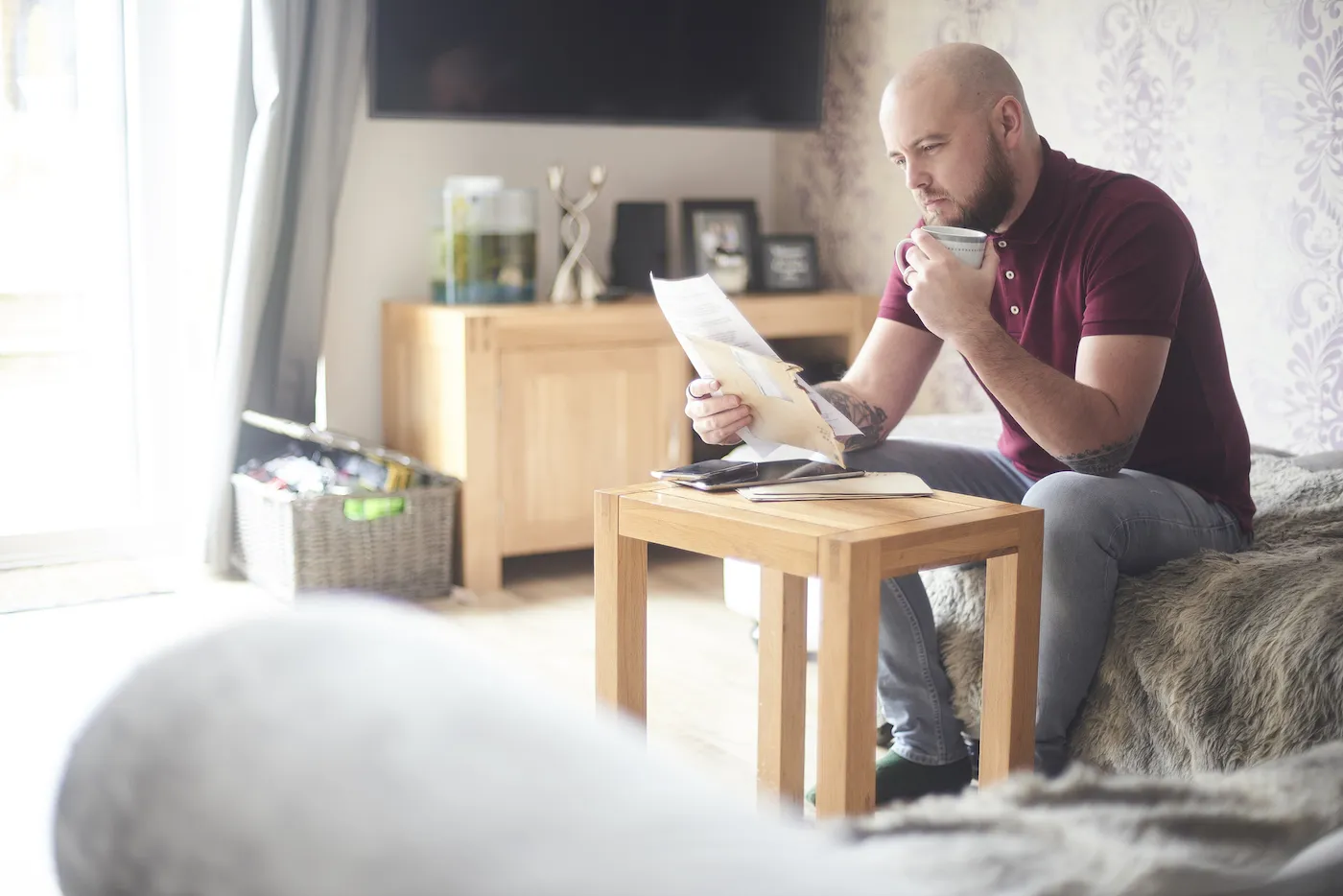 Man reading his paper credit card statement while sitting at a small table