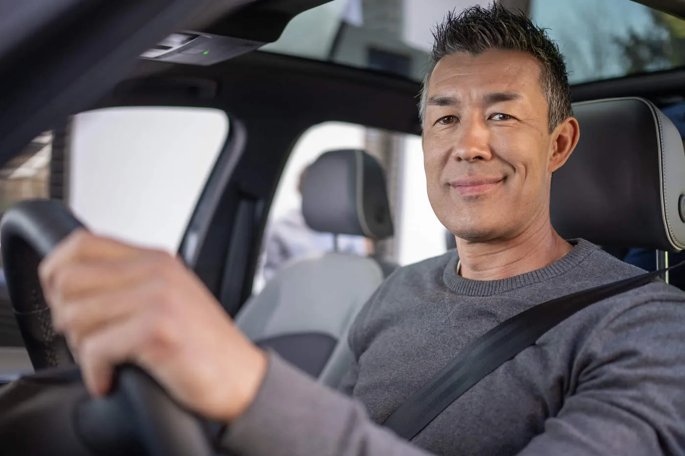 Man seated on driver's seat of a car.