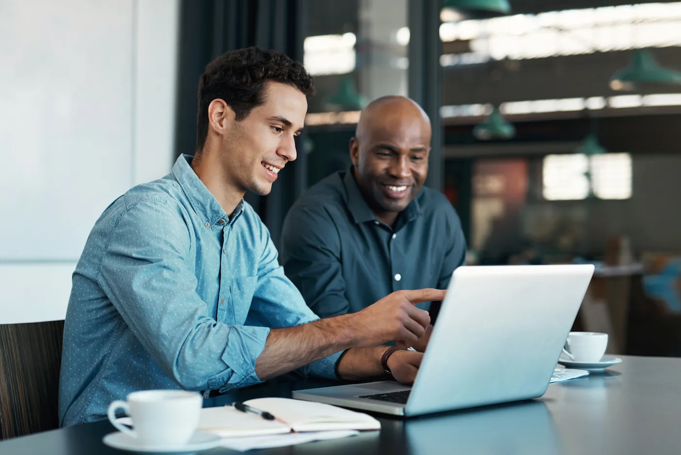 Two men discussing the minimum deposit for a CD. Sitting at a desk in front of a laptop.