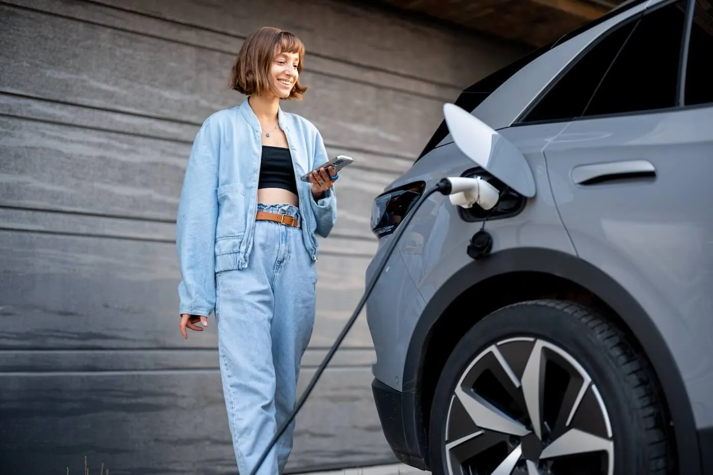 Smiling young woman charging her electric vehicle