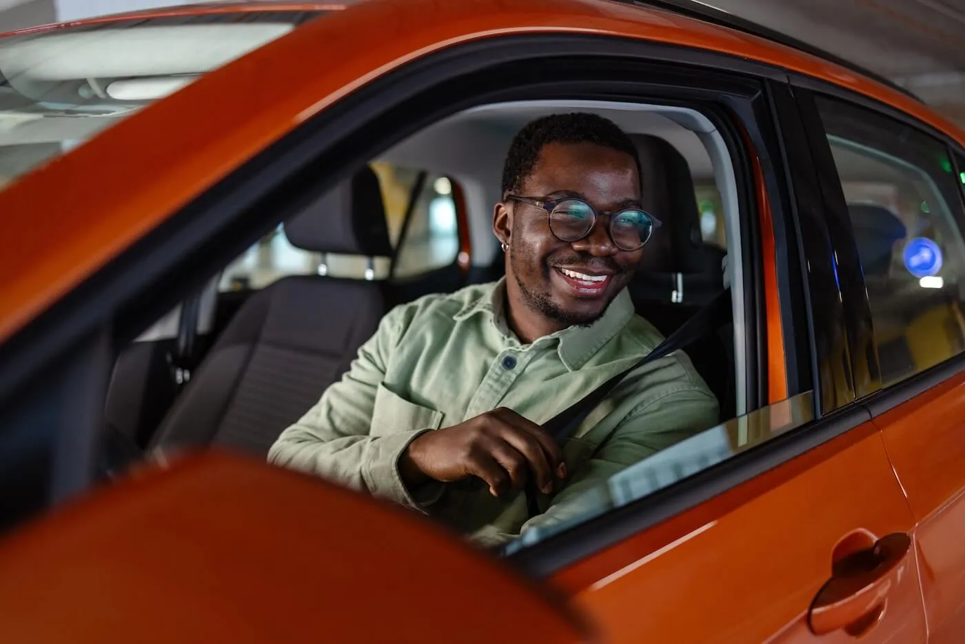 Young man in the orange car fastening his seatbelt