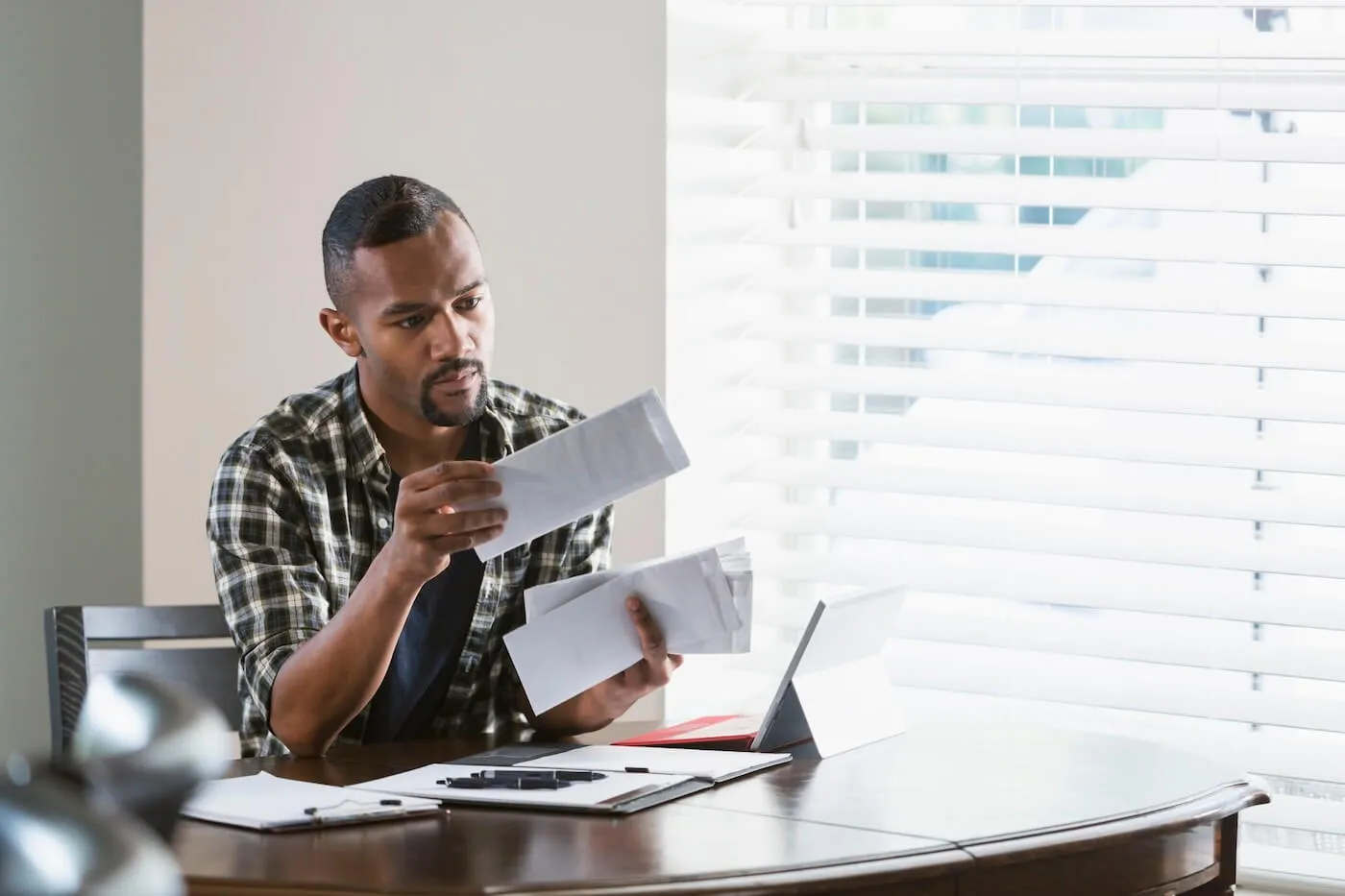 Concerned young man reviewing his mail in a home office