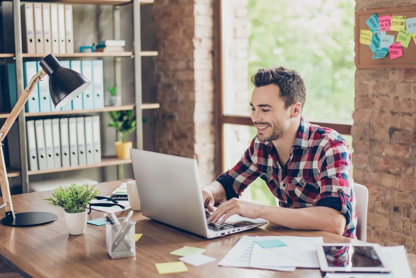 Smiling young man using his laptop in the home office