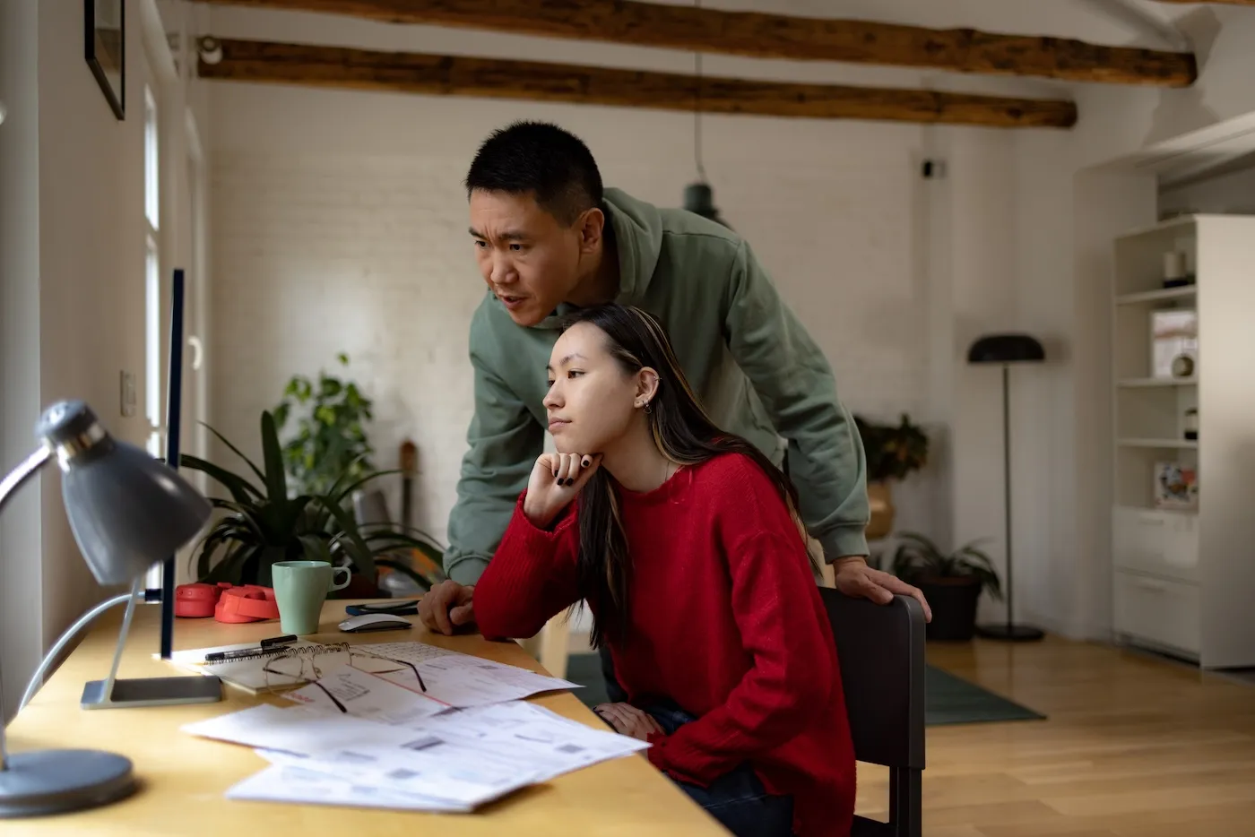 Young couple using desktop PC while working on their home finances.