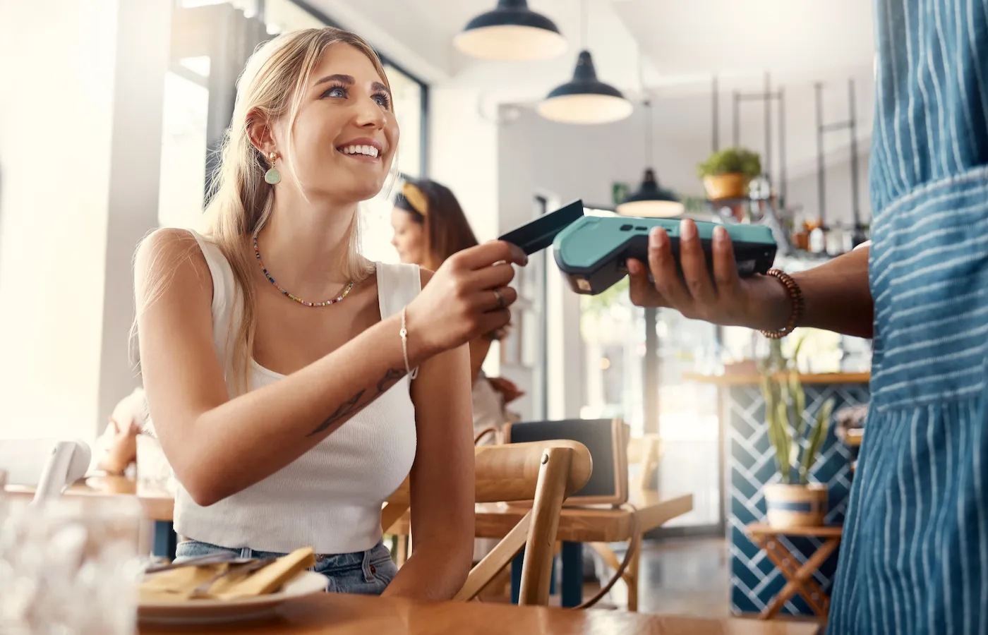 Shot of a young woman making a card payment using a nfc machine