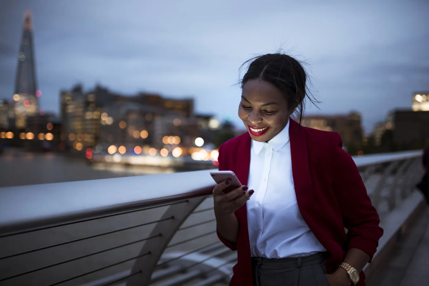 Front view photo of a woman using smartphone in London at dusk.