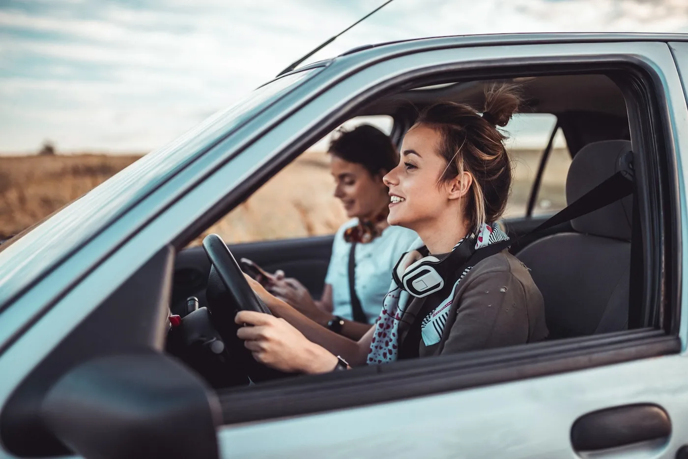 Two sisters driving a car and enjoying a summer road trip.