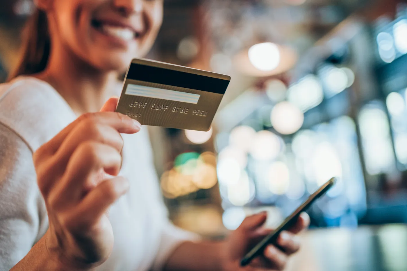 Portrait of a young woman holding her replacement credit card in focus.