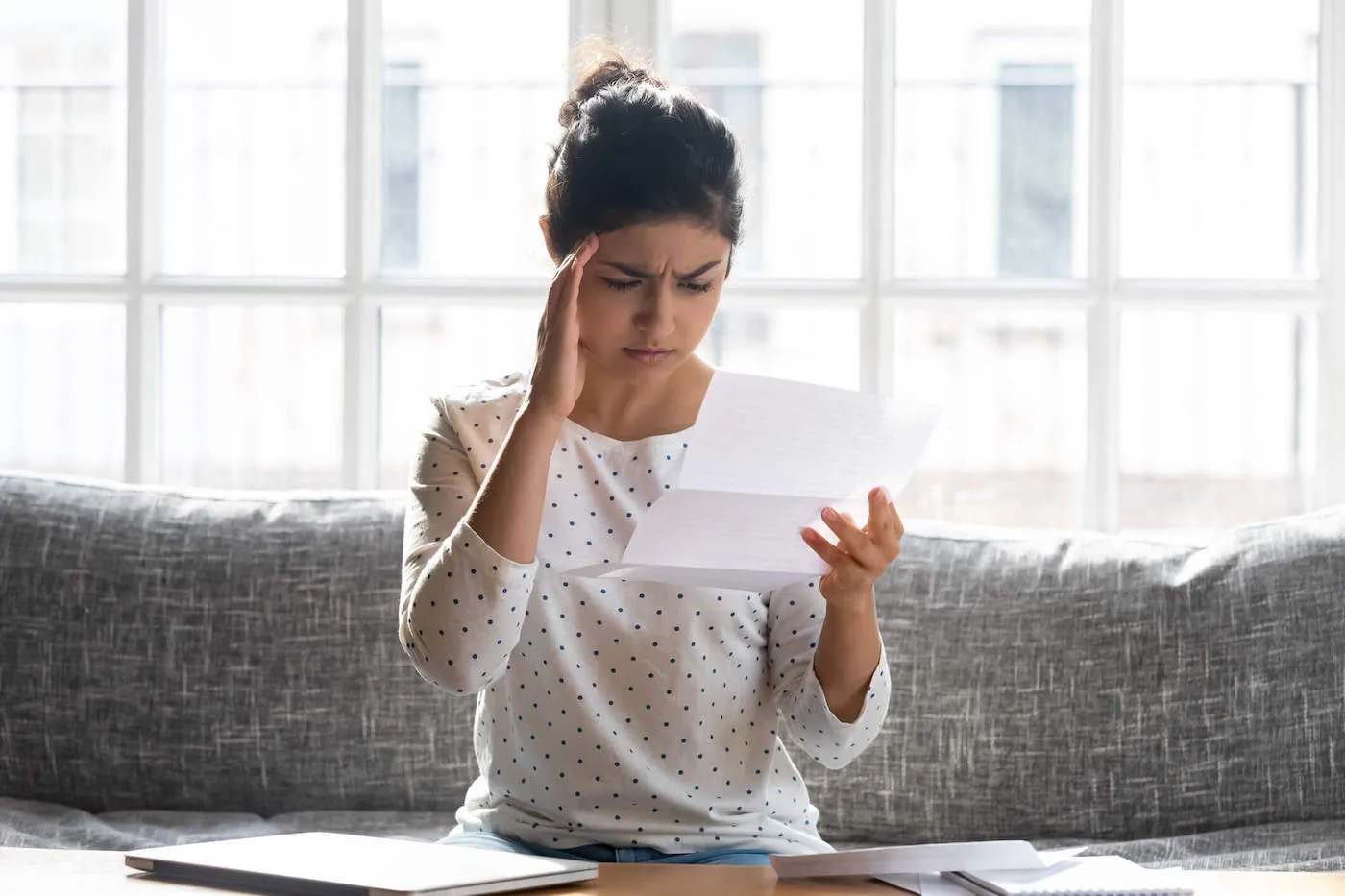 Seated concerned woman considering zombie debt.