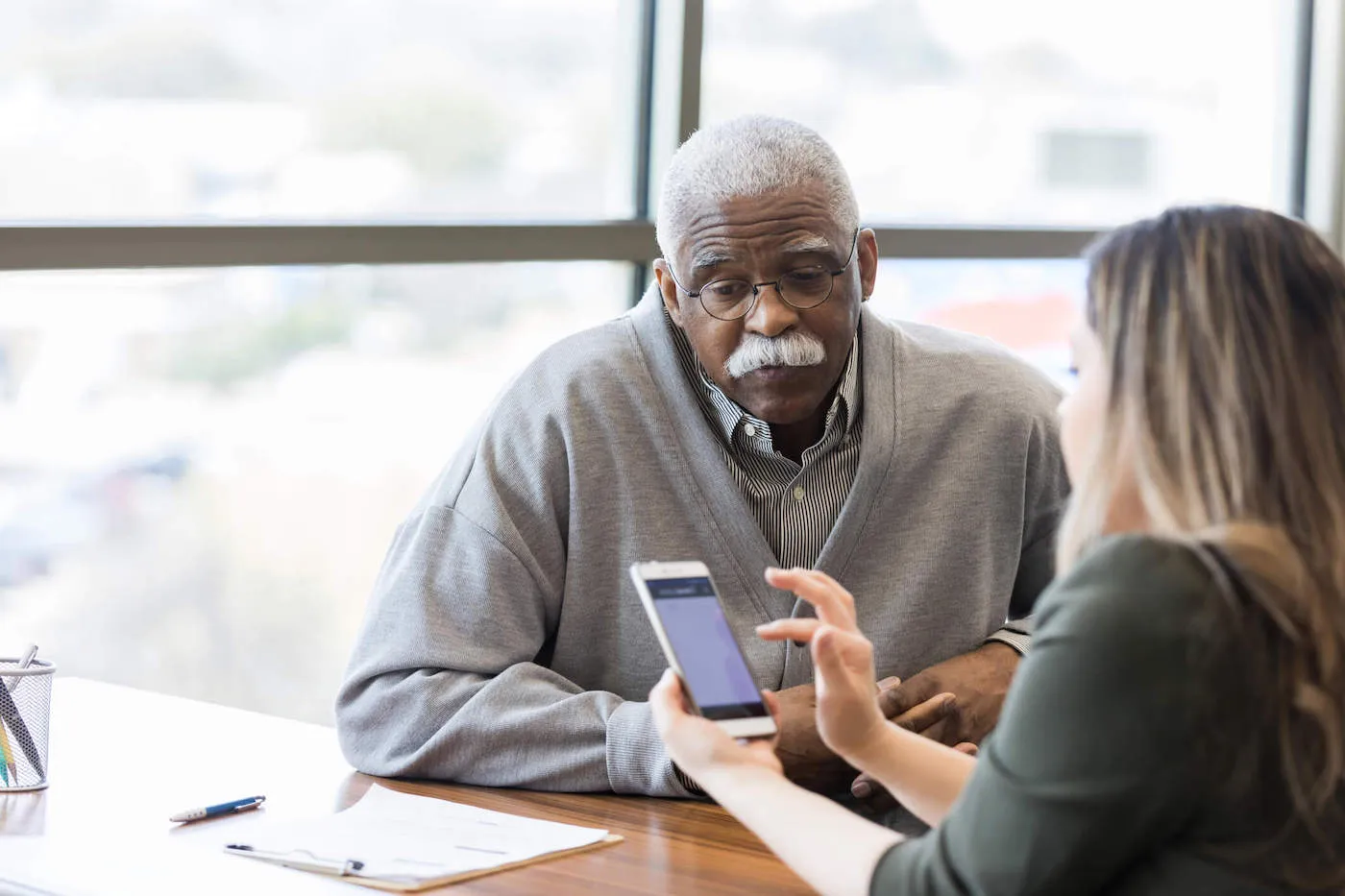 Seated elderly man meating with insurance agent.