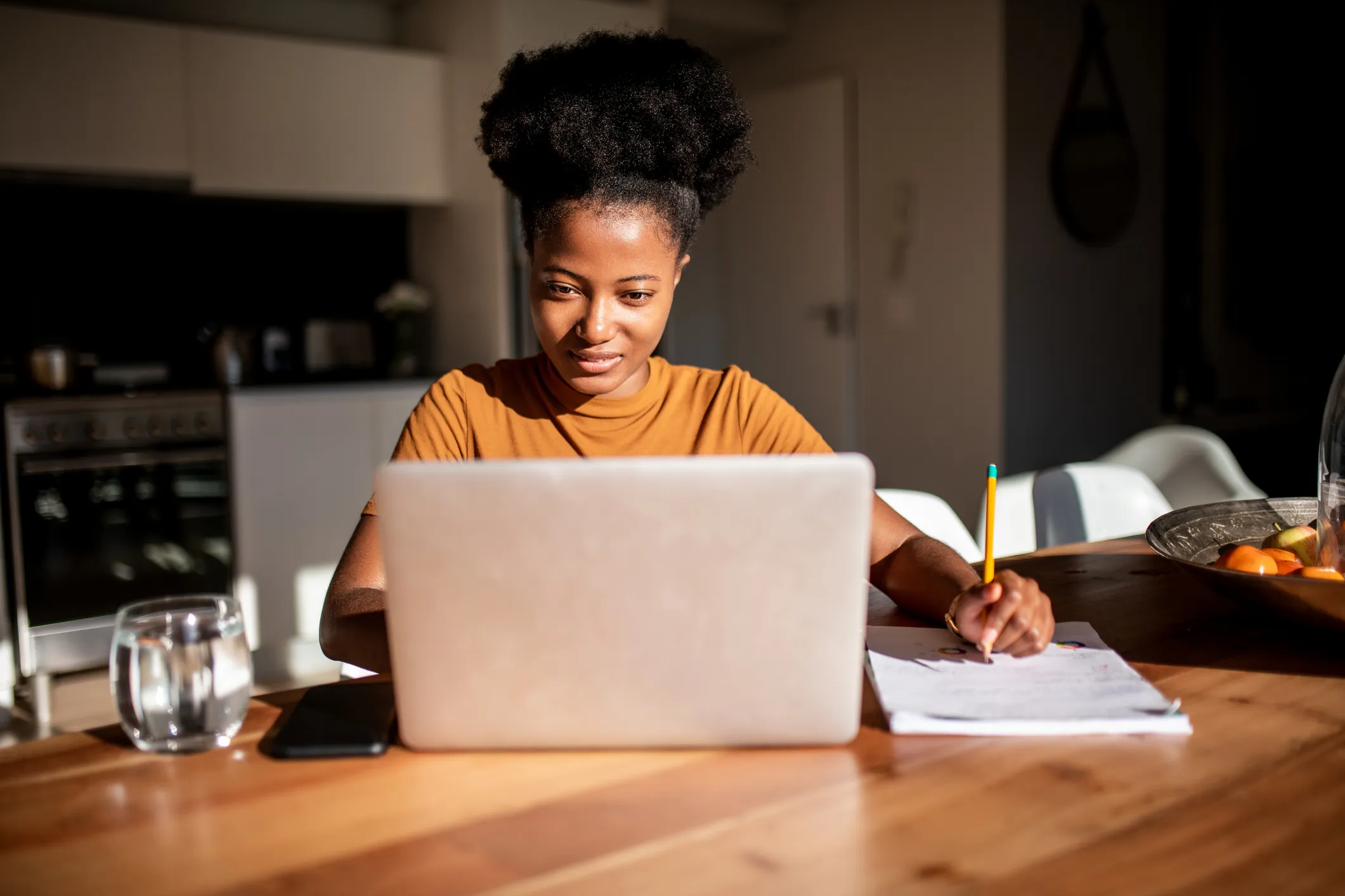 Young woman reading from the computer and taking notes at her notebook