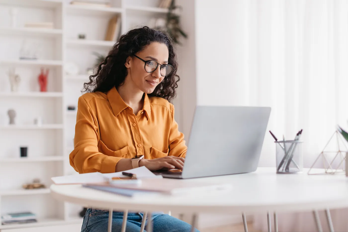 A woman deciding between paying off debt and saving money while working on her laptop.